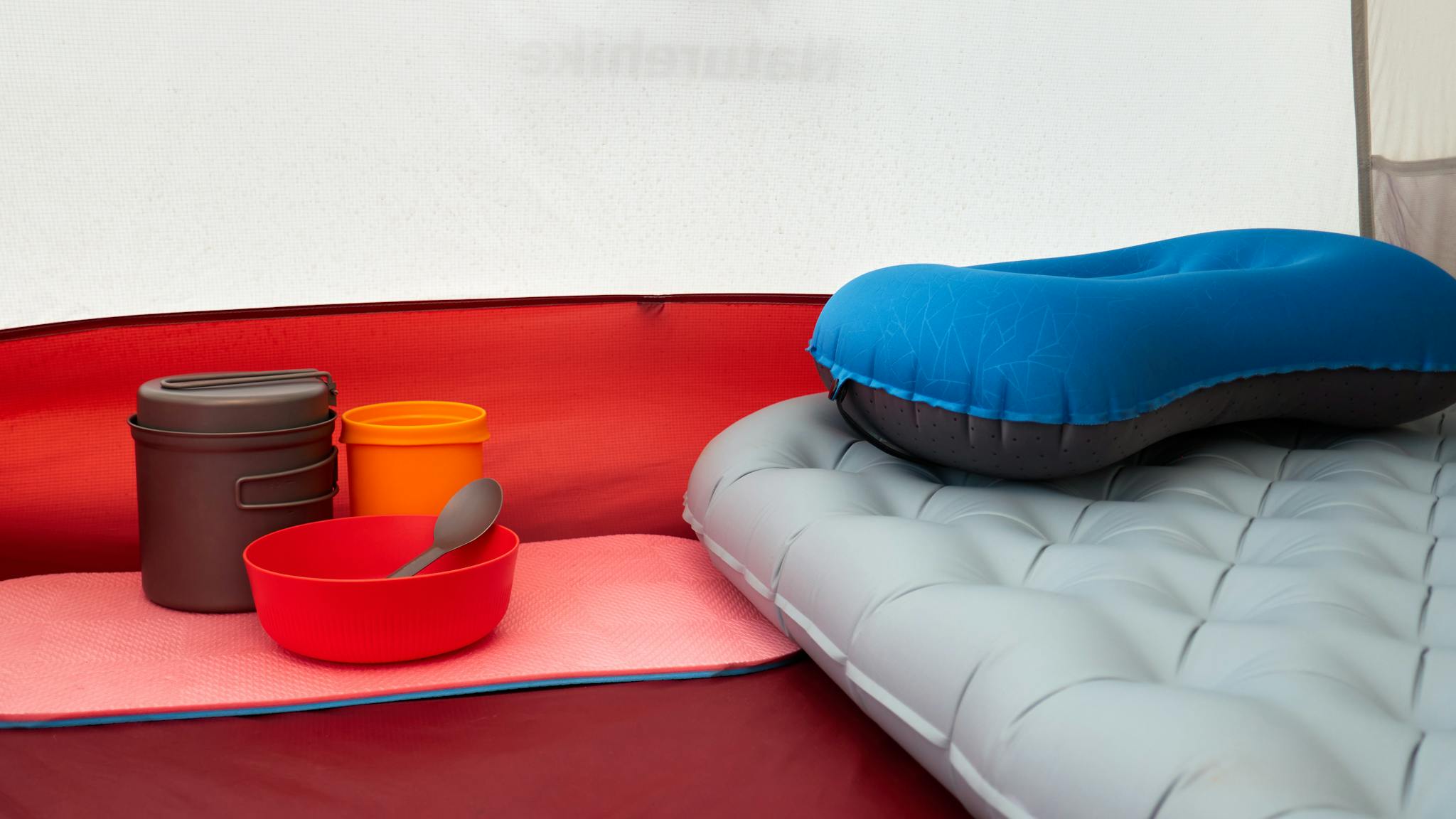 Inside a tent with inflatable pillow, cookware, and sleeping pad, ideal for camping.