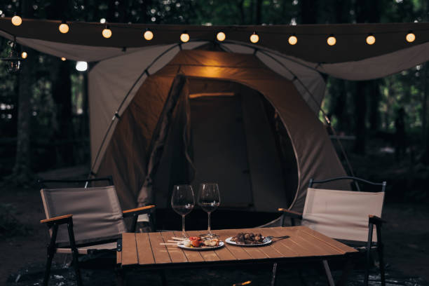 2 wine glasses on the table in camping nature at twilight. by the stream.